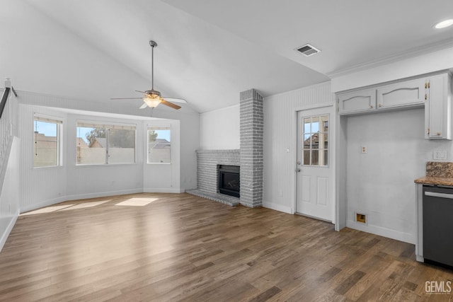 unfurnished living room featuring visible vents, plenty of natural light, dark wood-type flooring, and a brick fireplace