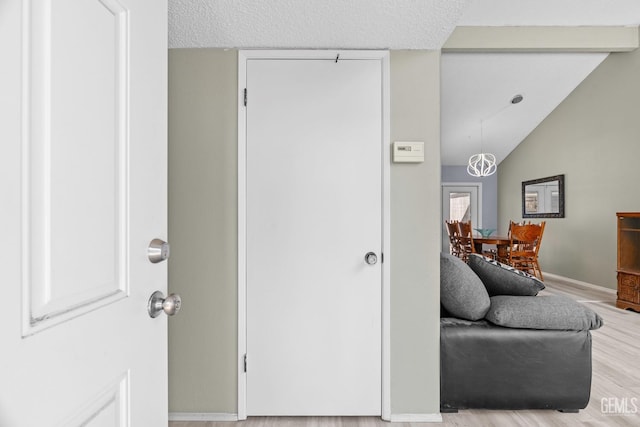 interior space featuring a textured ceiling, lofted ceiling with beams, baseboards, and wood finished floors