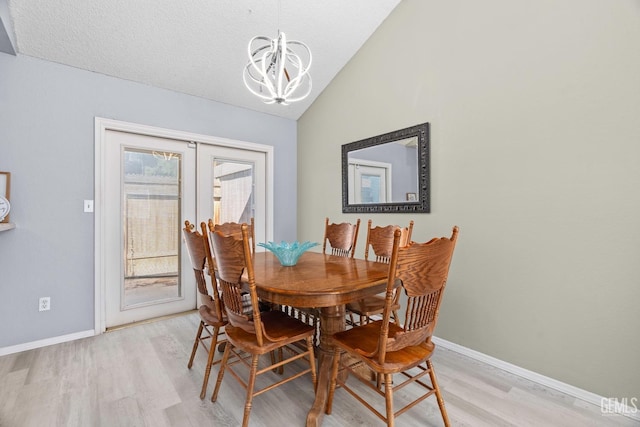 dining area with french doors, light wood-style flooring, an inviting chandelier, vaulted ceiling, and baseboards