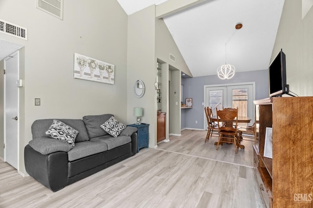 living room featuring high vaulted ceiling, wood finished floors, visible vents, and baseboards