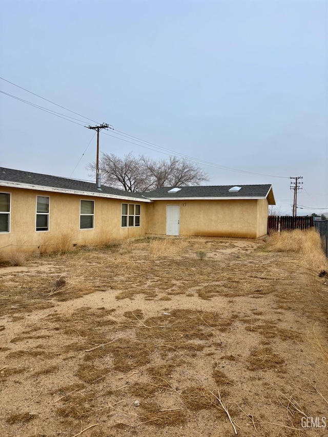 rear view of house with fence and stucco siding