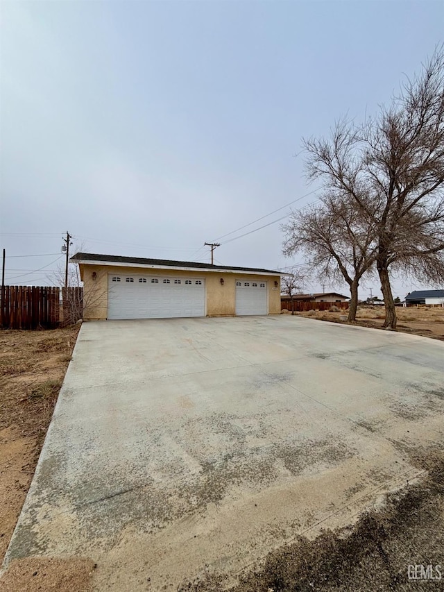 view of front of home with fence, stucco siding, and a garage