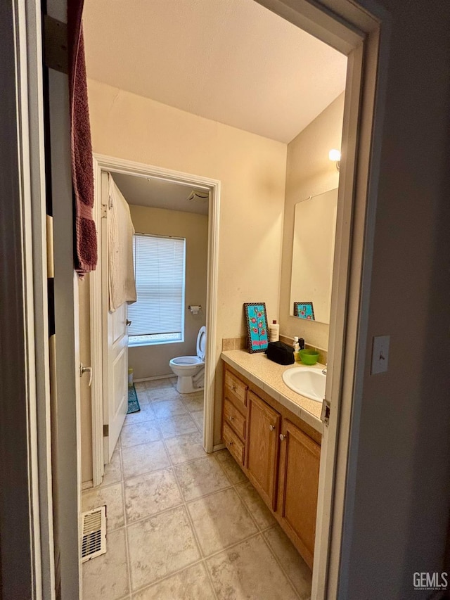 bathroom with vanity, toilet, visible vents, and bath / shower combo with glass door