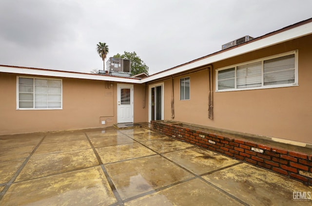 back of property with a patio, central AC, and stucco siding