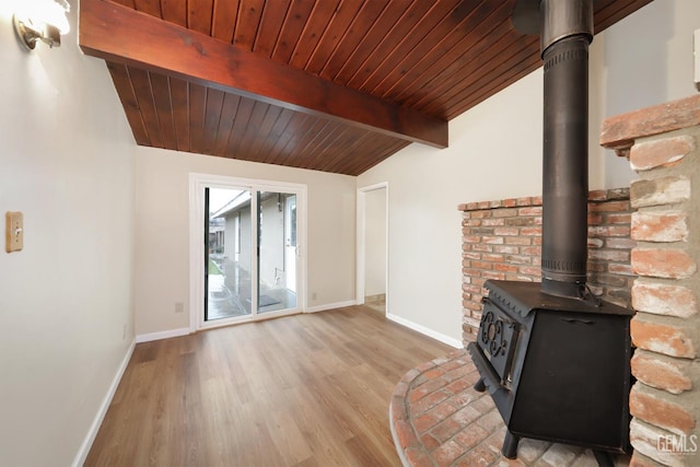 unfurnished living room with light wood finished floors, baseboards, wood ceiling, a wood stove, and vaulted ceiling with beams