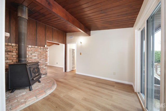 unfurnished living room with a wood stove, light wood-style floors, visible vents, and baseboards