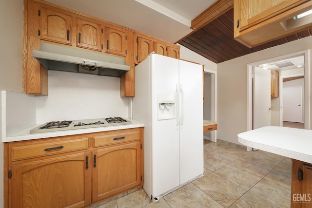 kitchen featuring light countertops, brown cabinetry, vaulted ceiling, white appliances, and under cabinet range hood