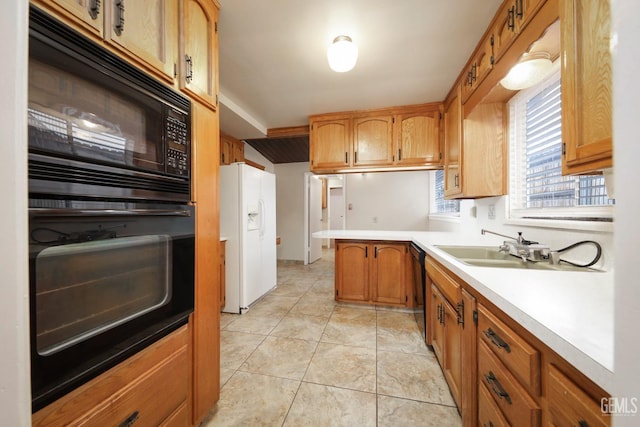 kitchen featuring brown cabinets, light countertops, black appliances, a sink, and light tile patterned flooring