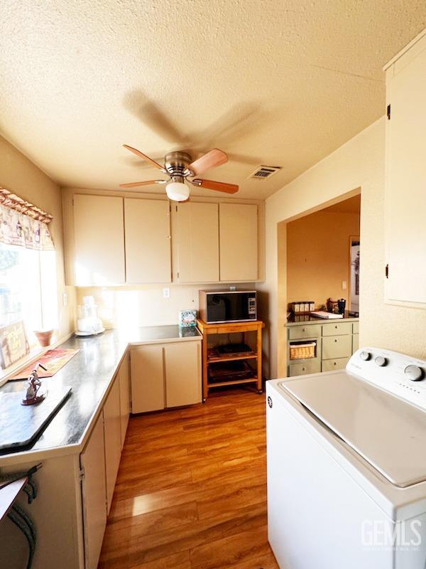 1041 Golden Gate Ave, Dos Palos, CA 93620 - kitchen featuring a ceiling fan, washer / clothes dryer, visible vents, black microwave, and light wood-type flooring
