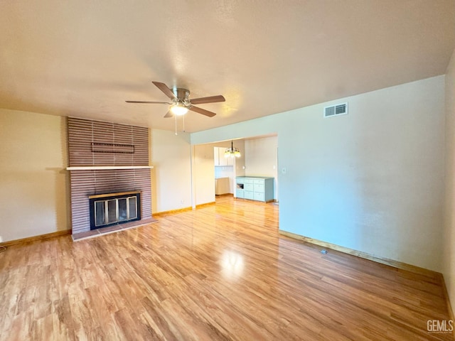 1041 Golden Gate Ave, Dos Palos, CA 93620 - unfurnished living room with a ceiling fan, light wood-style flooring, and a brick fireplace