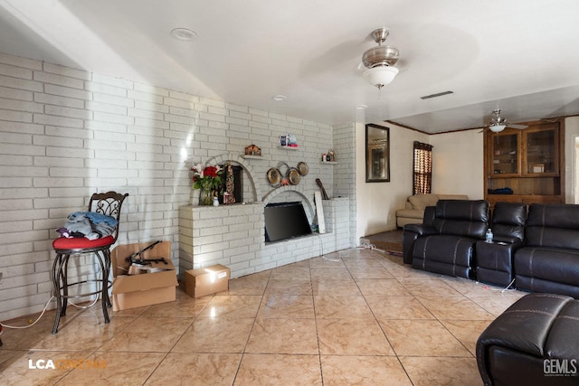 living room featuring ceiling fan, brick wall, and visible vents