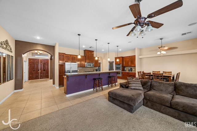 living area with arched walkways, visible vents, recessed lighting, ceiling fan, and light tile patterned floors