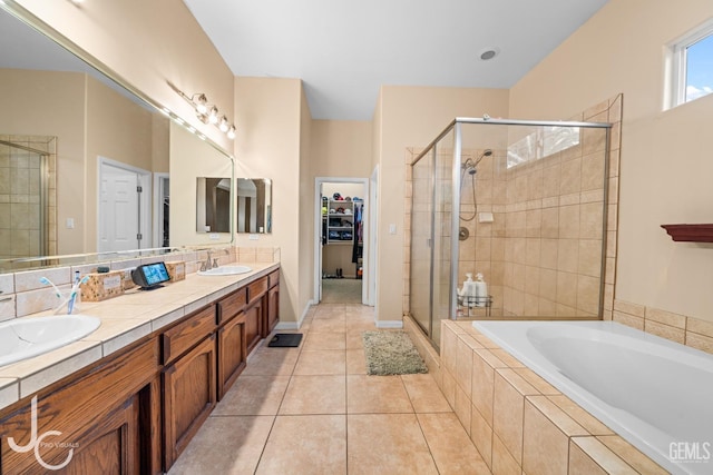 full bathroom featuring a walk in closet, a bath, tile patterned flooring, and a stall shower