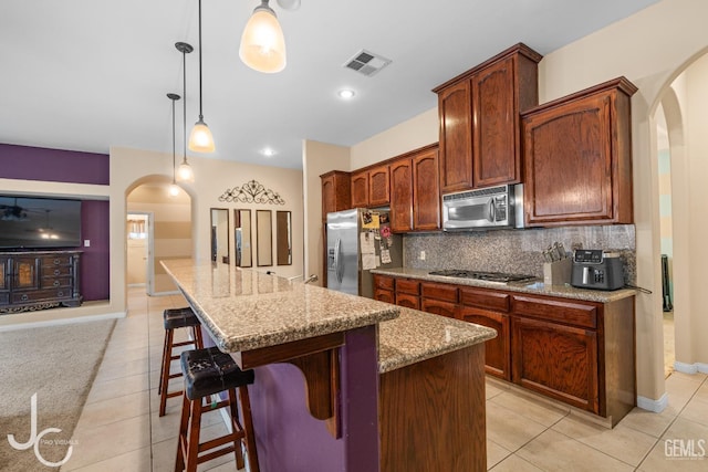 kitchen with arched walkways, visible vents, stainless steel appliances, and light tile patterned floors