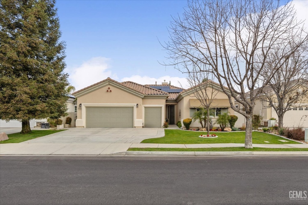 mediterranean / spanish-style home featuring solar panels, a garage, and a front yard