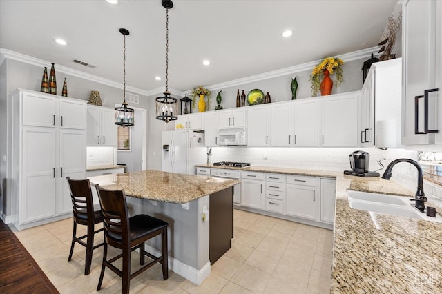 kitchen featuring pendant lighting, white appliances, sink, a kitchen island, and white cabinetry