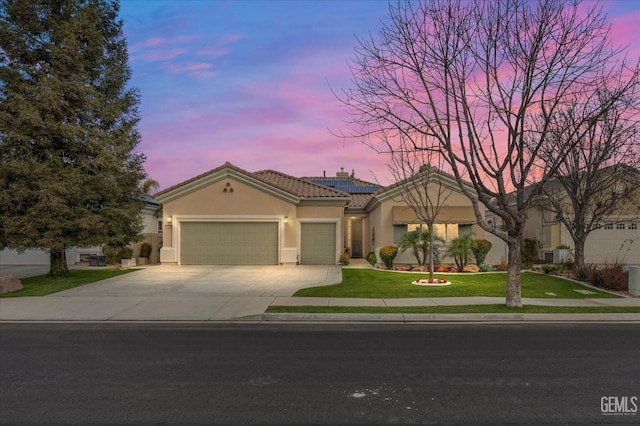 view of front of property with a lawn, solar panels, and a garage