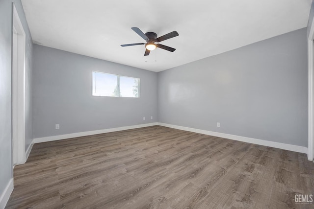 empty room with ceiling fan, baseboards, and wood finished floors