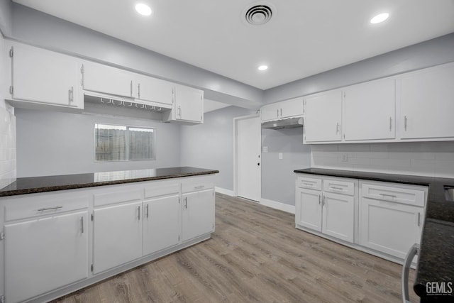 kitchen featuring light wood-style floors, white cabinets, visible vents, and decorative backsplash