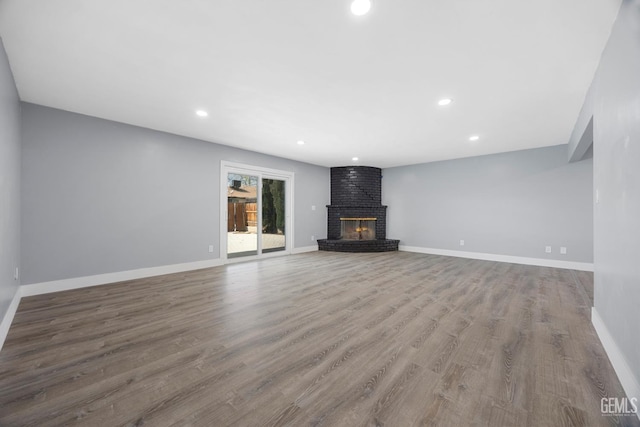 unfurnished living room featuring a fireplace, baseboards, wood finished floors, and recessed lighting