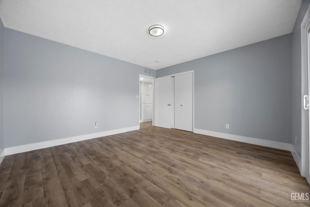 unfurnished bedroom with a closet, baseboards, and wood finished floors