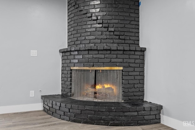 interior details with a fireplace, wood finished floors, and baseboards