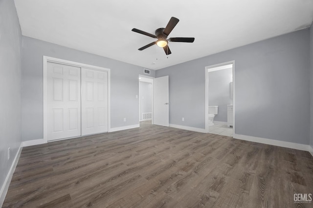 unfurnished bedroom with a closet, wood finished floors, visible vents, and baseboards