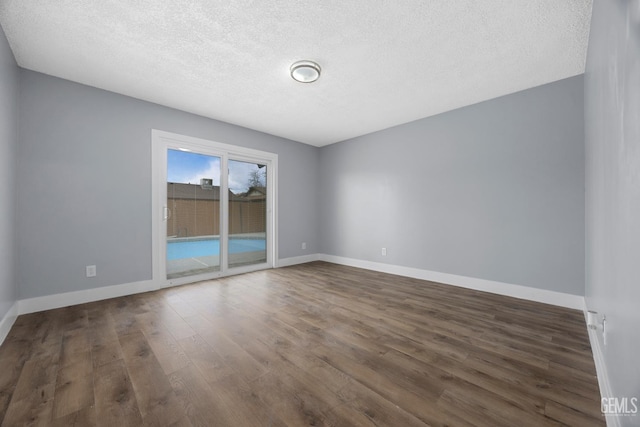 spare room featuring a textured ceiling, baseboards, and wood finished floors