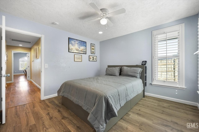 bedroom with dark wood-type flooring, ceiling fan, and a textured ceiling