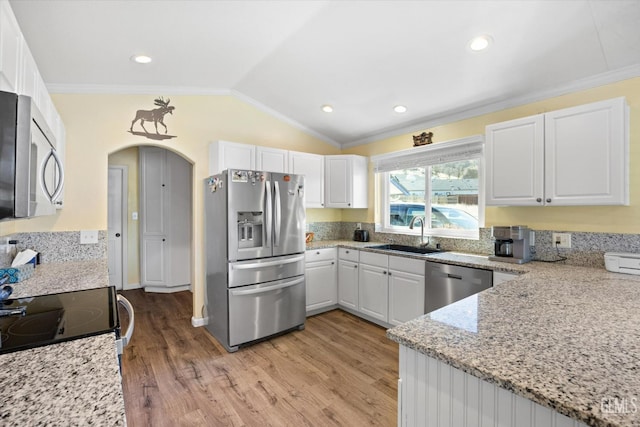 kitchen featuring lofted ceiling, sink, appliances with stainless steel finishes, light stone countertops, and white cabinets