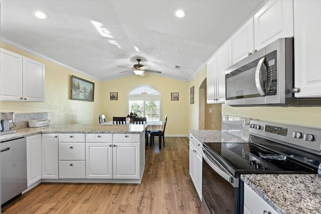 kitchen featuring lofted ceiling, stainless steel appliances, white cabinets, and light wood-type flooring