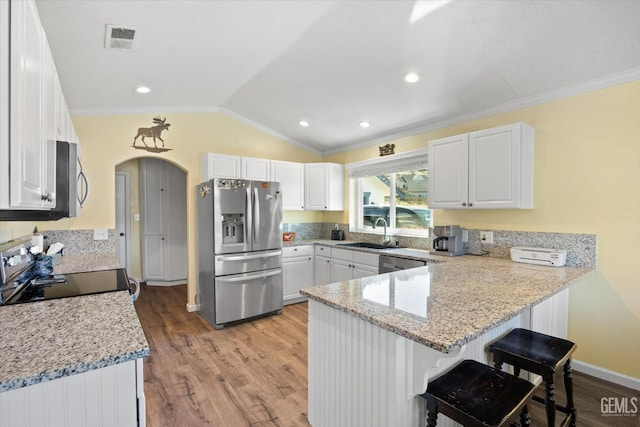 kitchen with sink, a breakfast bar area, stainless steel appliances, white cabinets, and kitchen peninsula