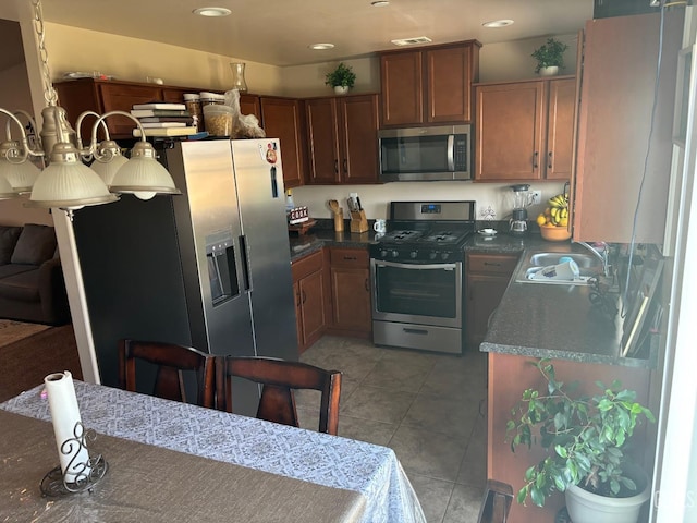 kitchen with dark countertops, light tile patterned floors, stainless steel appliances, and a sink