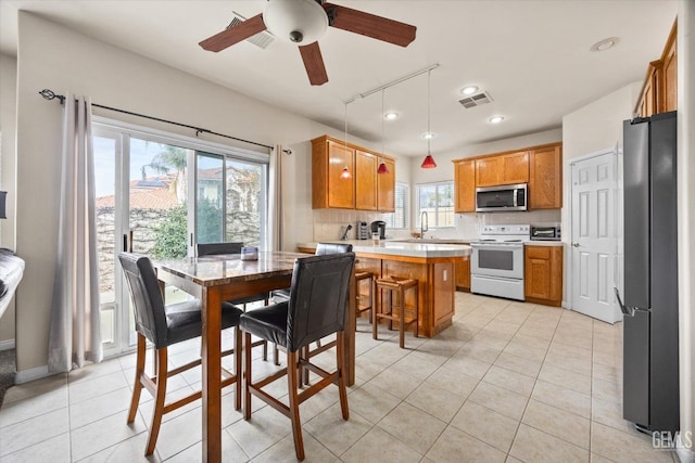 kitchen featuring a peninsula, light tile patterned floors, stainless steel appliances, and light countertops