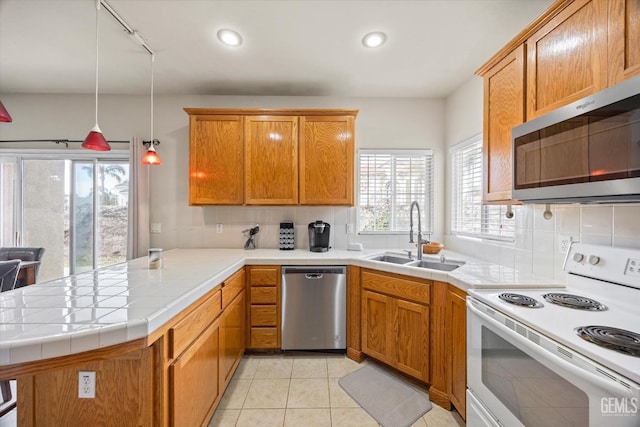 kitchen with light tile patterned floors, appliances with stainless steel finishes, a peninsula, a sink, and backsplash