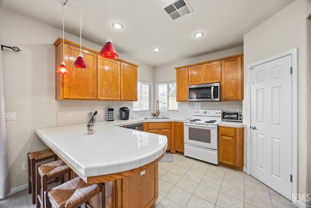 kitchen with visible vents, appliances with stainless steel finishes, a breakfast bar, a peninsula, and a sink