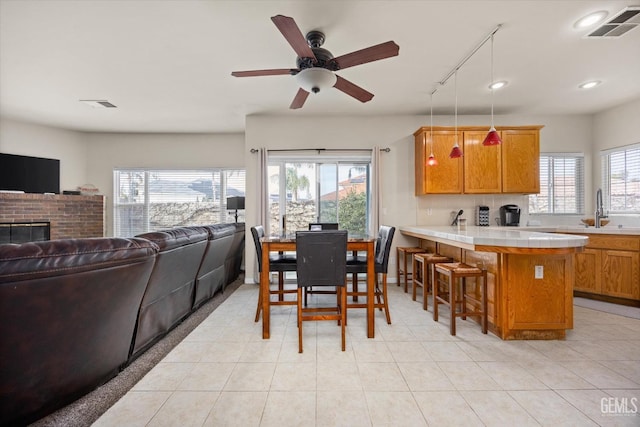 dining room featuring plenty of natural light, light tile patterned floors, a brick fireplace, and visible vents