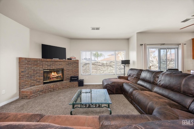 living area with a fireplace, carpet flooring, visible vents, and baseboards