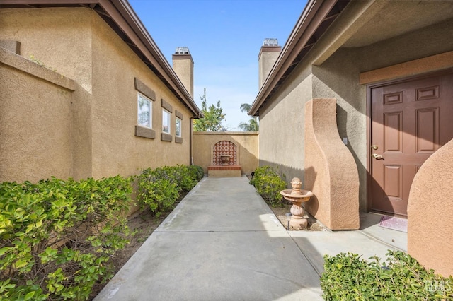 view of home's exterior with a gate, a chimney, and stucco siding