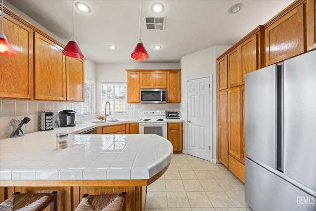 kitchen with visible vents, decorative backsplash, appliances with stainless steel finishes, a peninsula, and a sink