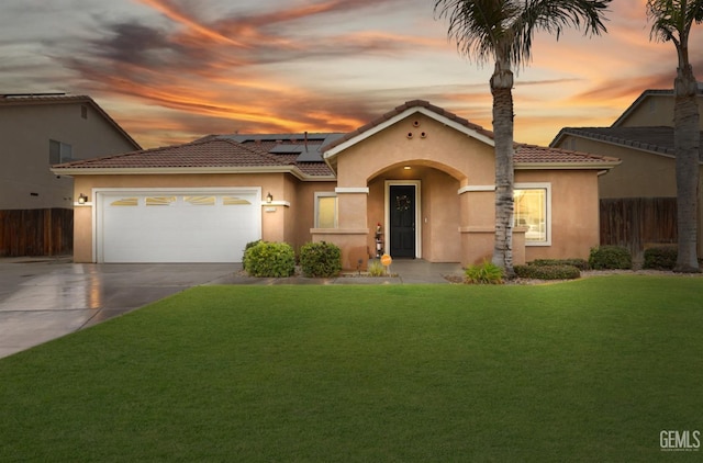 mediterranean / spanish house with a garage, a lawn, and solar panels