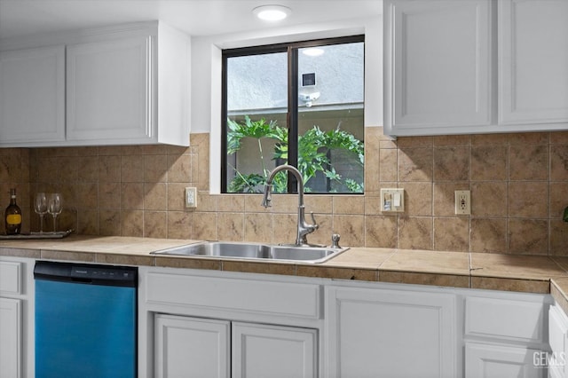 kitchen with dishwashing machine, backsplash, a sink, and white cabinets