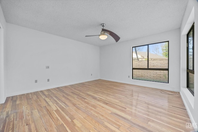 unfurnished room with baseboards, ceiling fan, light wood-style flooring, and a textured ceiling