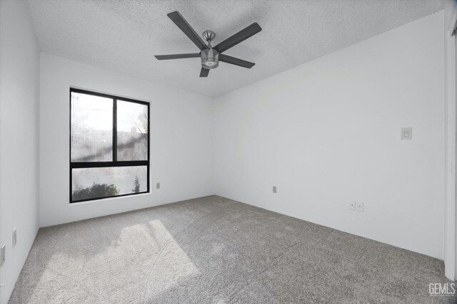 carpeted empty room featuring ceiling fan and a textured ceiling