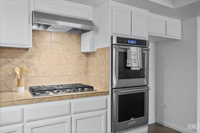 kitchen with stainless steel appliances, light countertops, decorative backsplash, white cabinetry, and ventilation hood