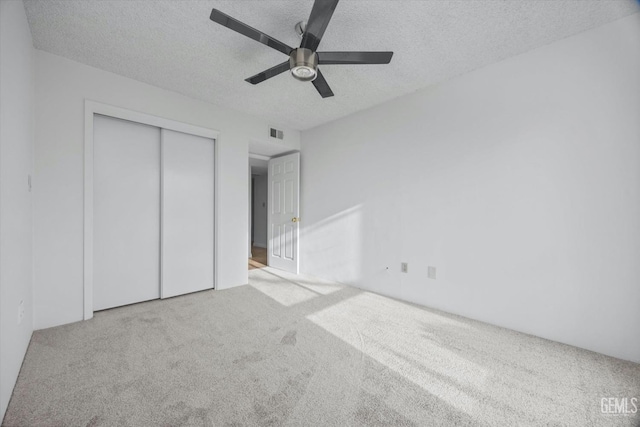 unfurnished bedroom featuring a textured ceiling, carpet floors, a closet, and visible vents