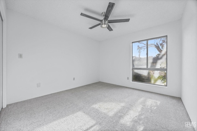 empty room with ceiling fan, a textured ceiling, and carpet flooring