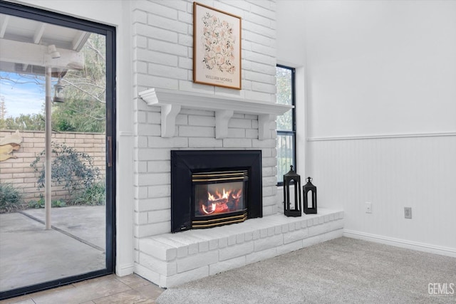 unfurnished living room with a wainscoted wall, a brick fireplace, and carpet flooring