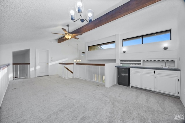 interior space with light colored carpet, dark countertops, a textured ceiling, white cabinetry, and ceiling fan with notable chandelier