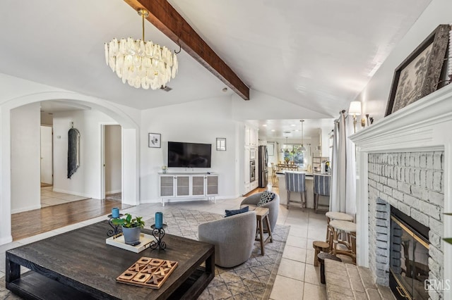 tiled living room with a fireplace, lofted ceiling with beams, and a notable chandelier